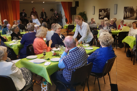 En sal fylld med människor som sitter till bords, där de blir serverade mat