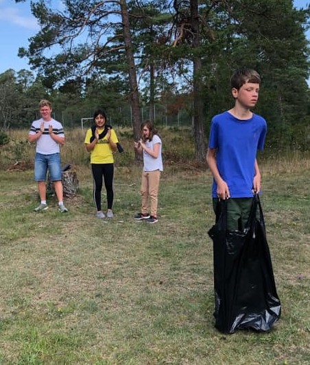 Deltagaren Carl Gunnar hoppar säck och hejas på av sina lagkamrater i laget ”De aktiva”: Emil, Angelina och Liv.