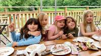 5 vita glad förskolebarn sitter bredvid varann vid långbord, smaskar kladdig glass.